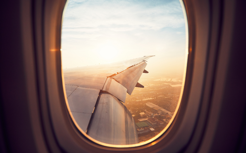 A view of an aeroplane wing and the sky through the window
