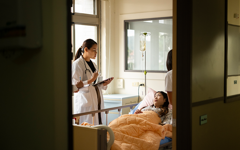 A young Asian female doctor and a young male doctor are rounding in the hospital ward