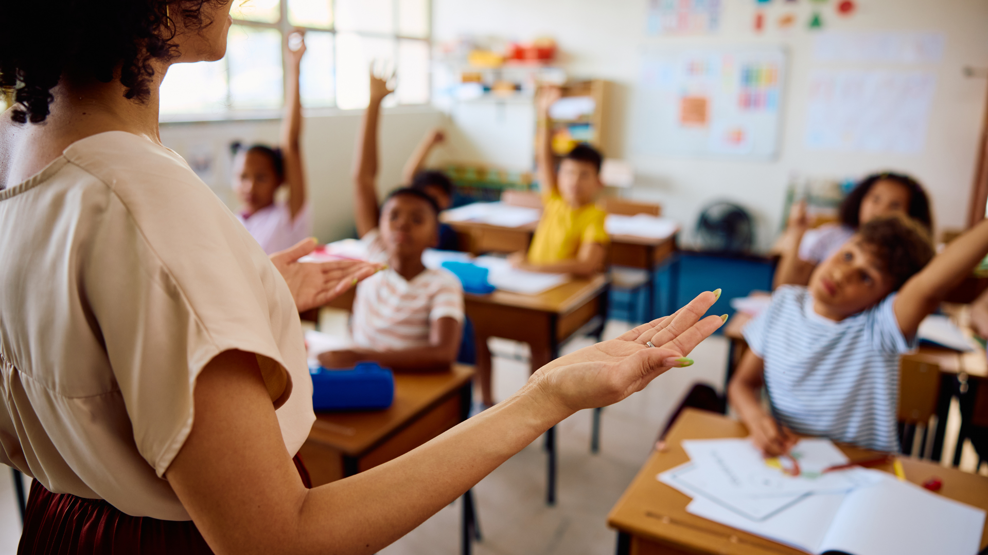 A female teacher gestures while engaging students in a classroom