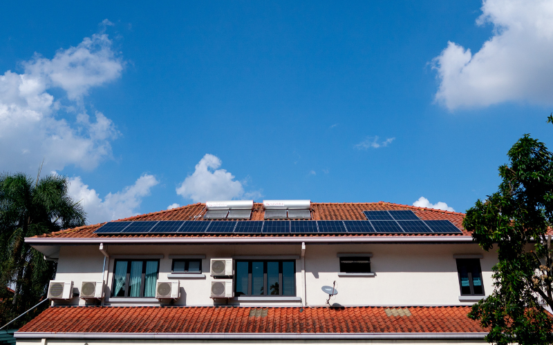 A row of solar panels installed on the roof of a modern suburban home