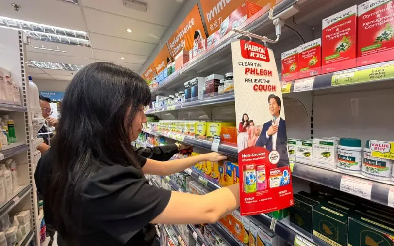 Zhi Xuan rearranges products during a shelf-merchandising exercise in Alpro's mock-up pharmacy