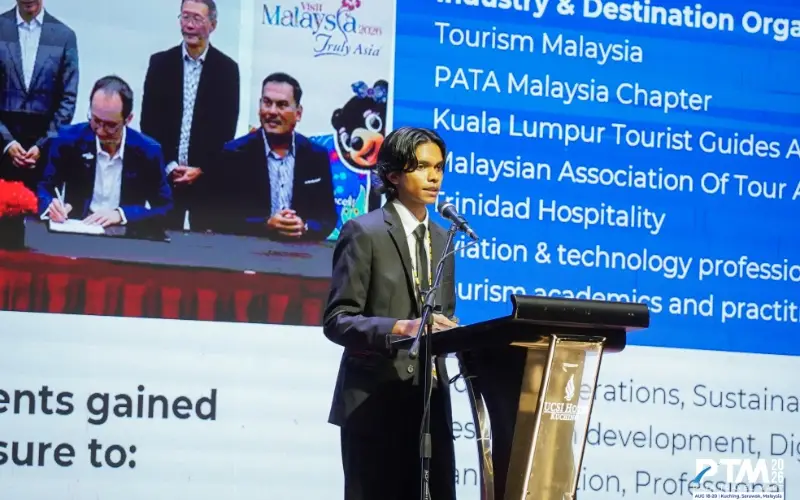 Abdulla Iyaan Ahmed speaking at a lectern at the PATA Youth Symposium 2026 in Kuching, Sarawak, with a slide listing industry and destination partners behind him