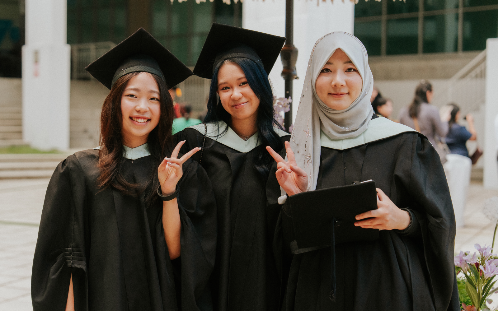 Three Taylor's female graduates posing in front of the camera