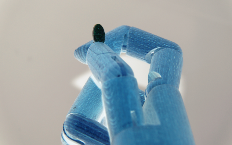 Robotic hand holding a single tablet, representing AI in drug discovery