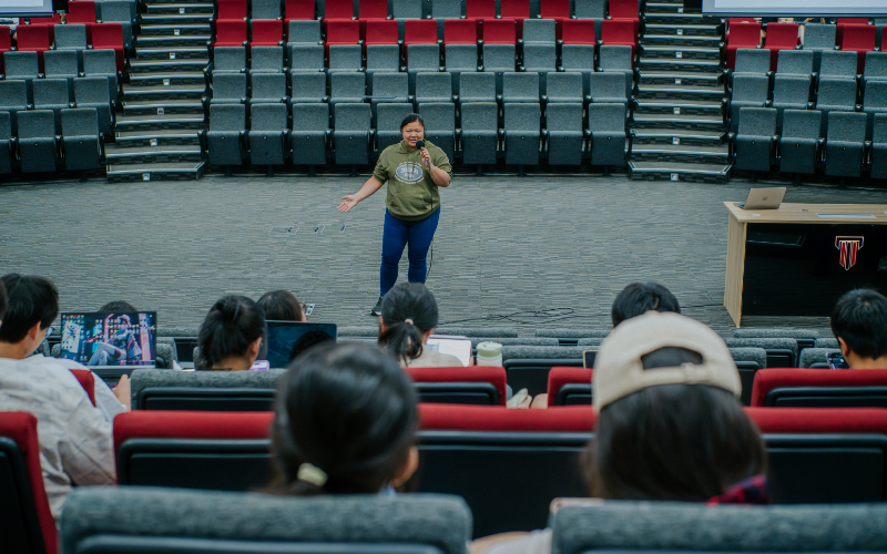 Speaker addressing students from the floor of a lecture theatre at Taylor's University