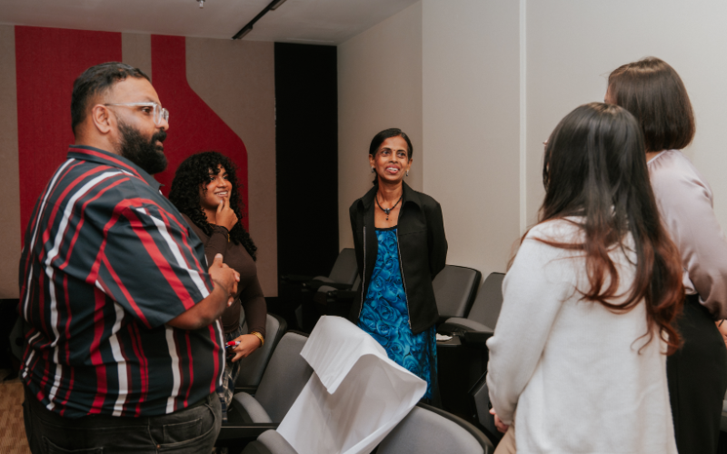Participants standing in conversation with a speaker between sessions of the programme