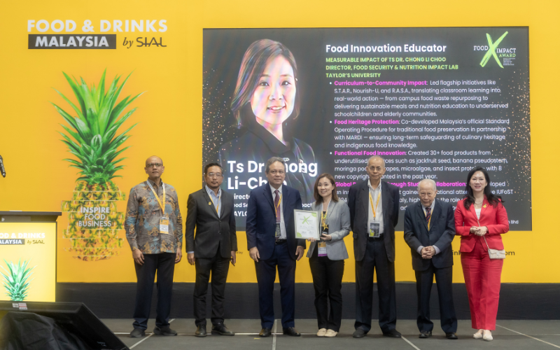 A group of seven formally dressed people stand on a stage at the Food & Drinks Malaysia by SIAL event.