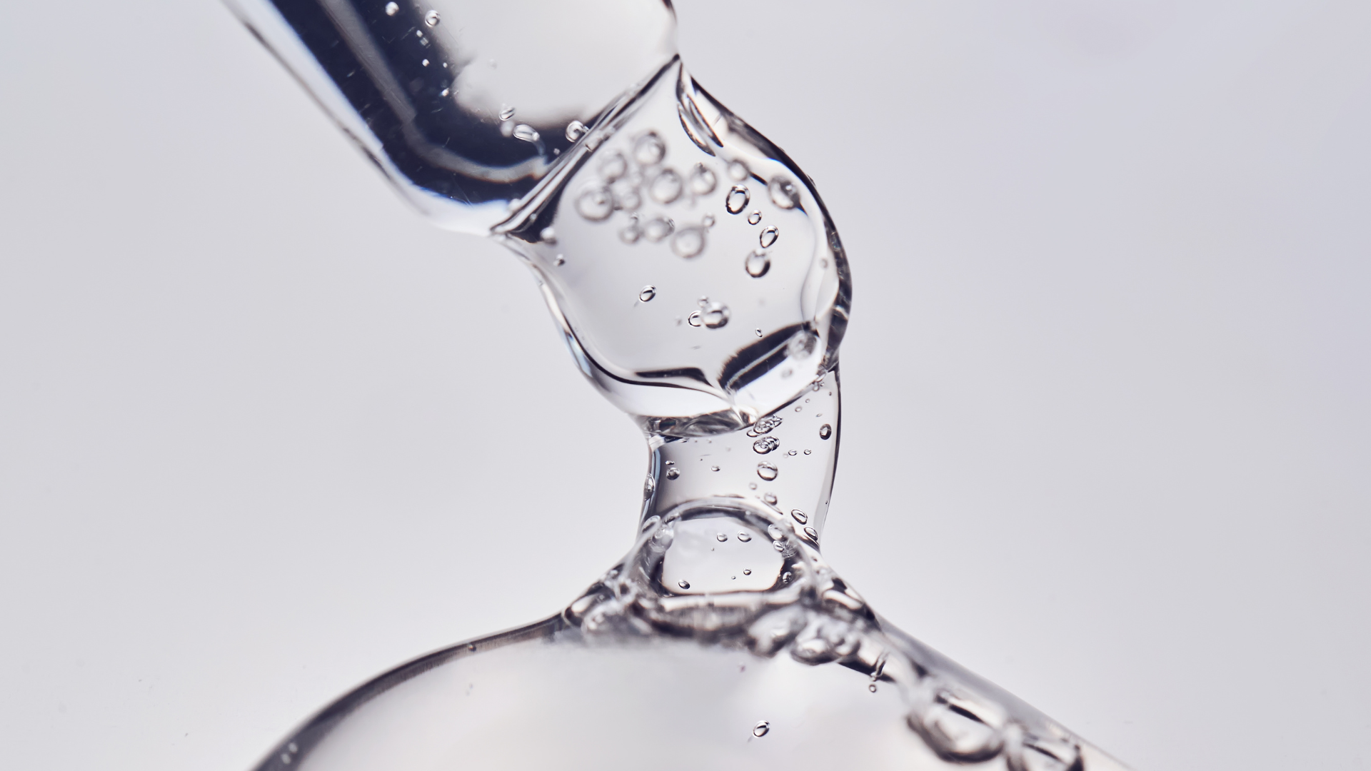 Clear serum dripping from a glass dropper