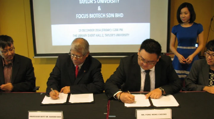 Representatives from Taylor's and Focus Biotech signing document