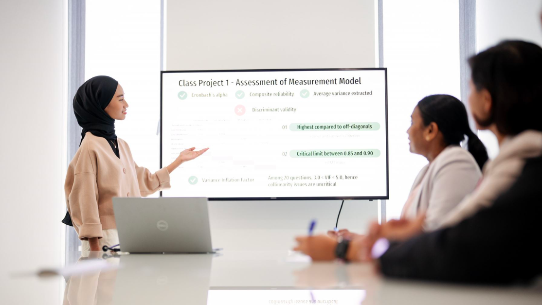 A student present business case studies to two others students in a meeting room