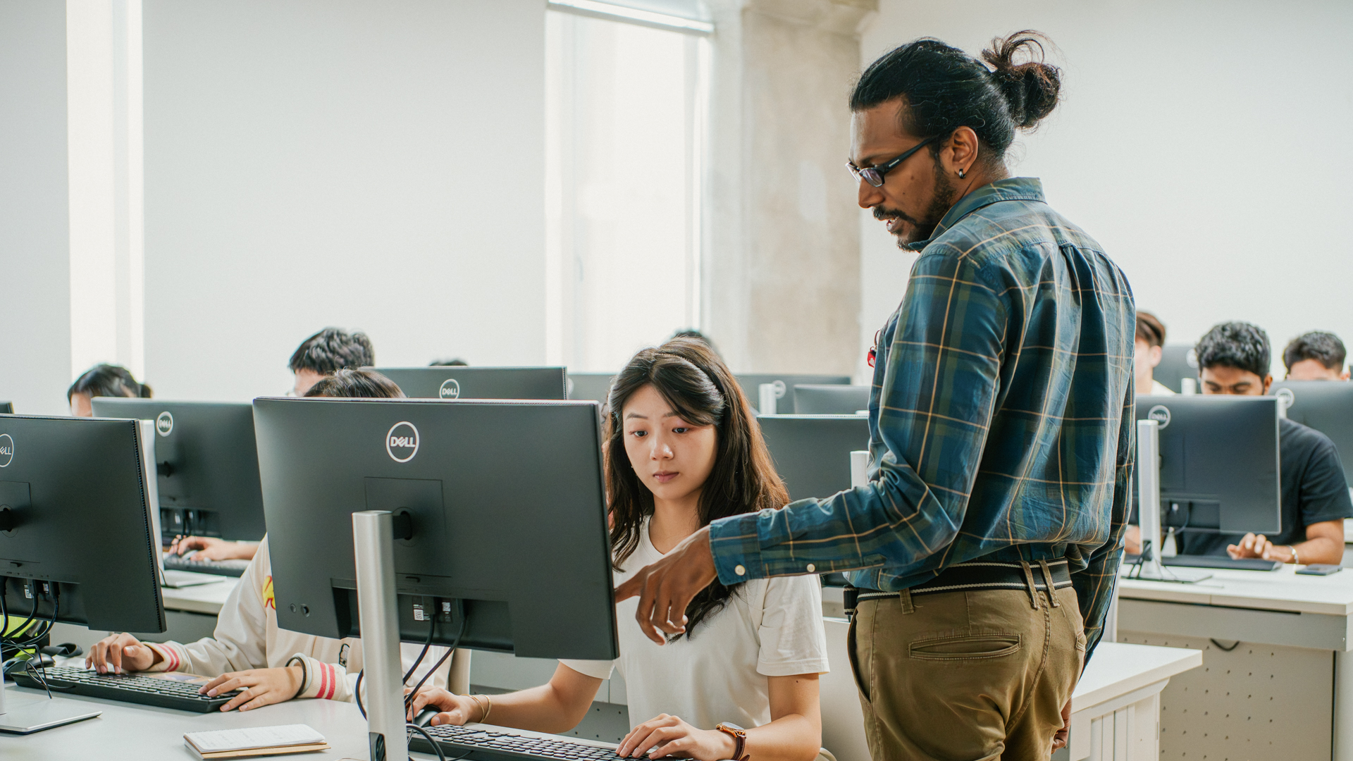 Taylor's computing lecturer guiding a student during computer lab class