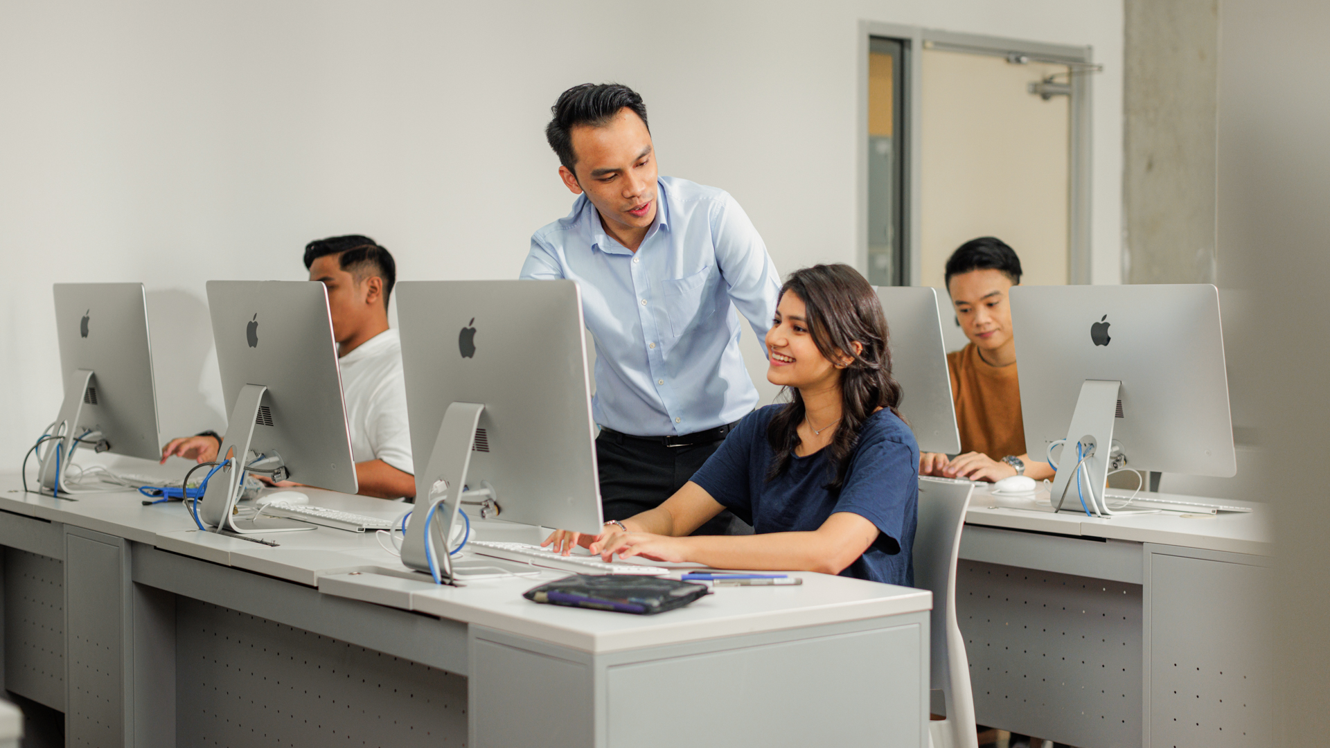 Taylor's lecturer guiding master's computing student in computer laboratory