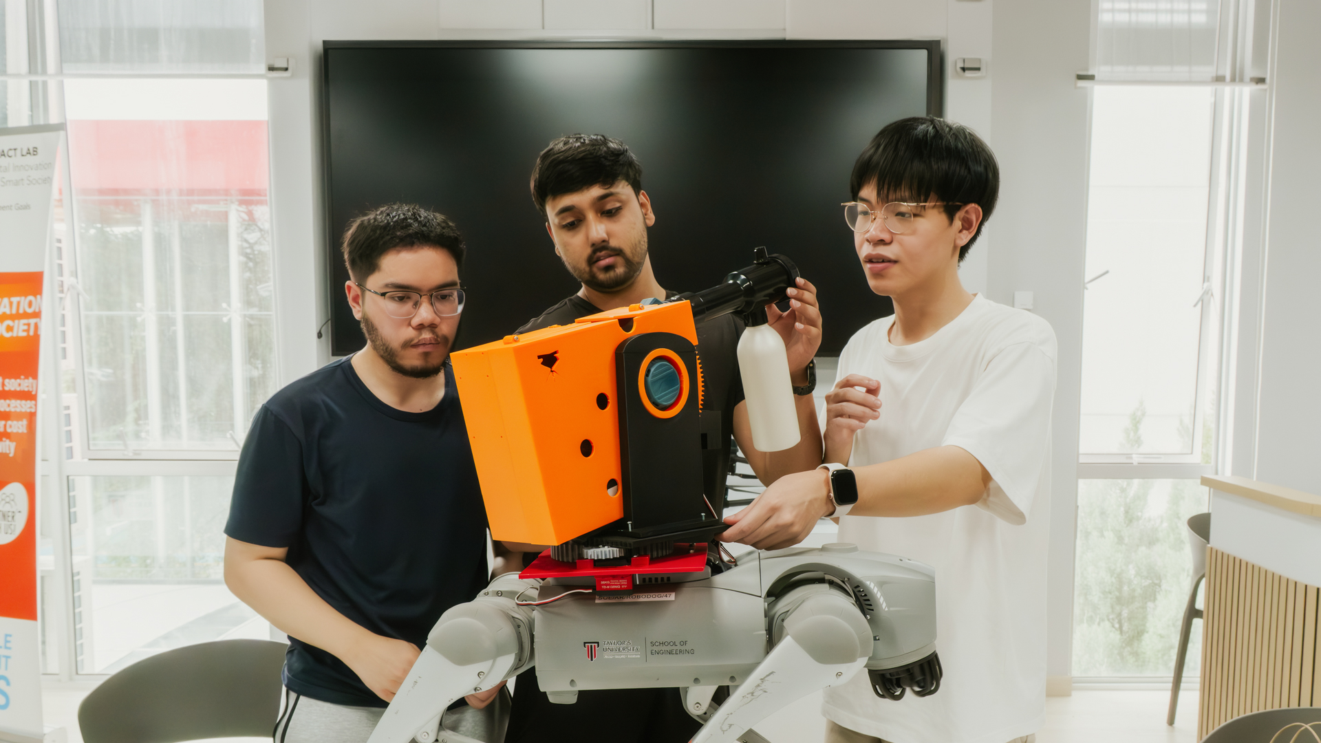 Taylor's University students collaborating on a robotics project with an advanced quadruped robotic dog in a modern innovation lab.
