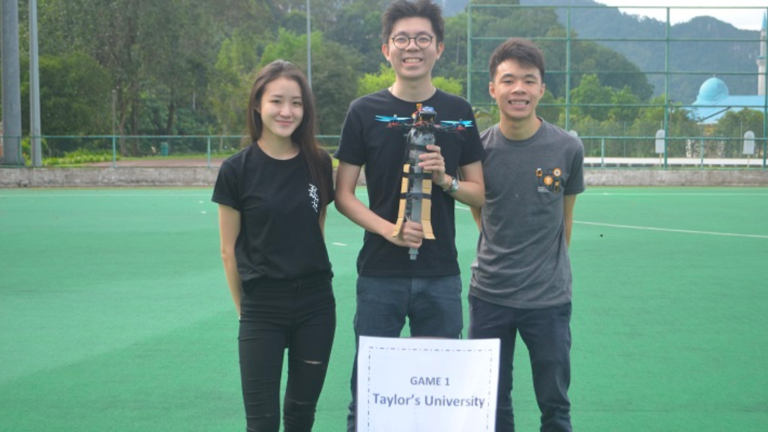 Three Taylor's School of Engineering students holding the model of the project