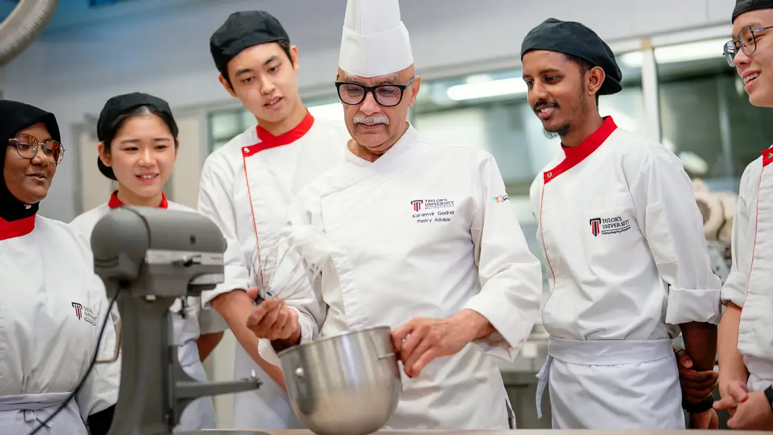 Taylor's culinary lecturer demonstrates way to prepare ingredient to the students