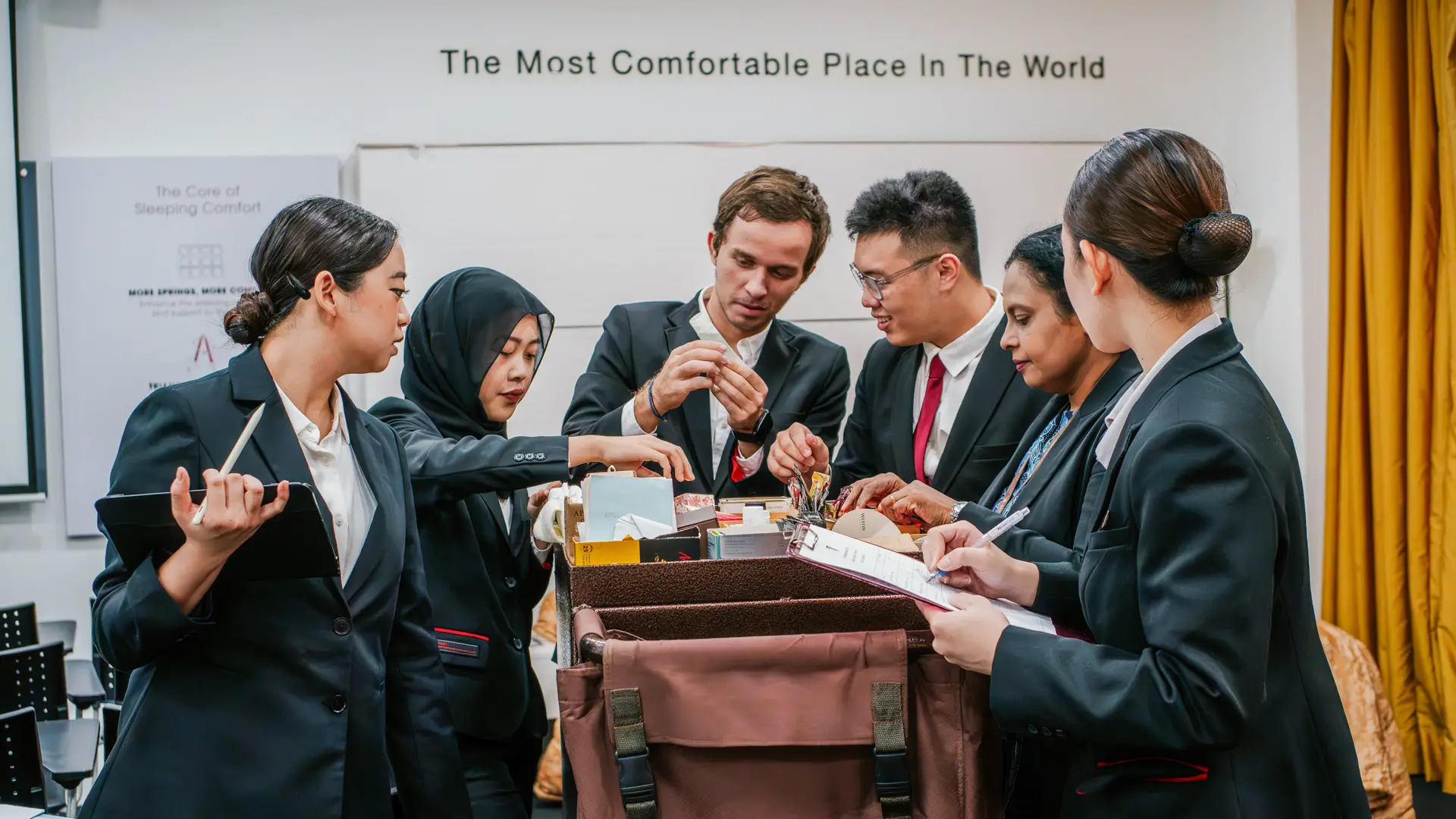 Taylor's University hospitality students in professional suits collaborating on a practical management exercise in a modern training environment.