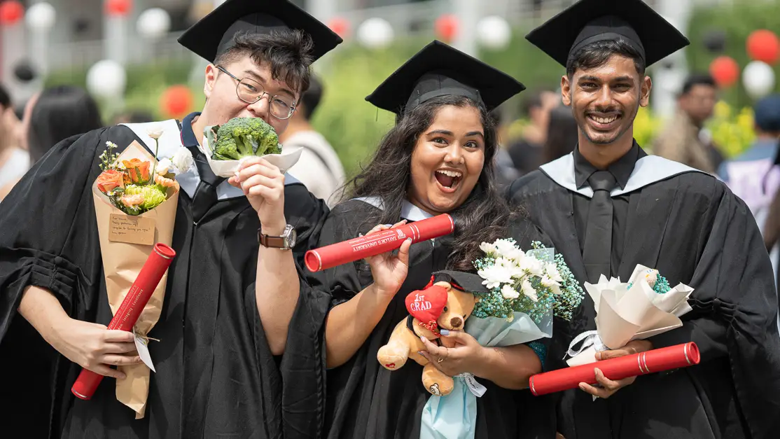 Taylor's hospitality student holding graduation scroll with peers
