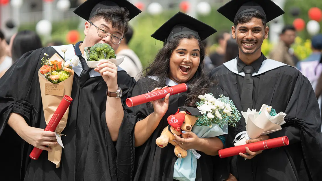 Taylor's hospitality student holding graduation scroll with peers