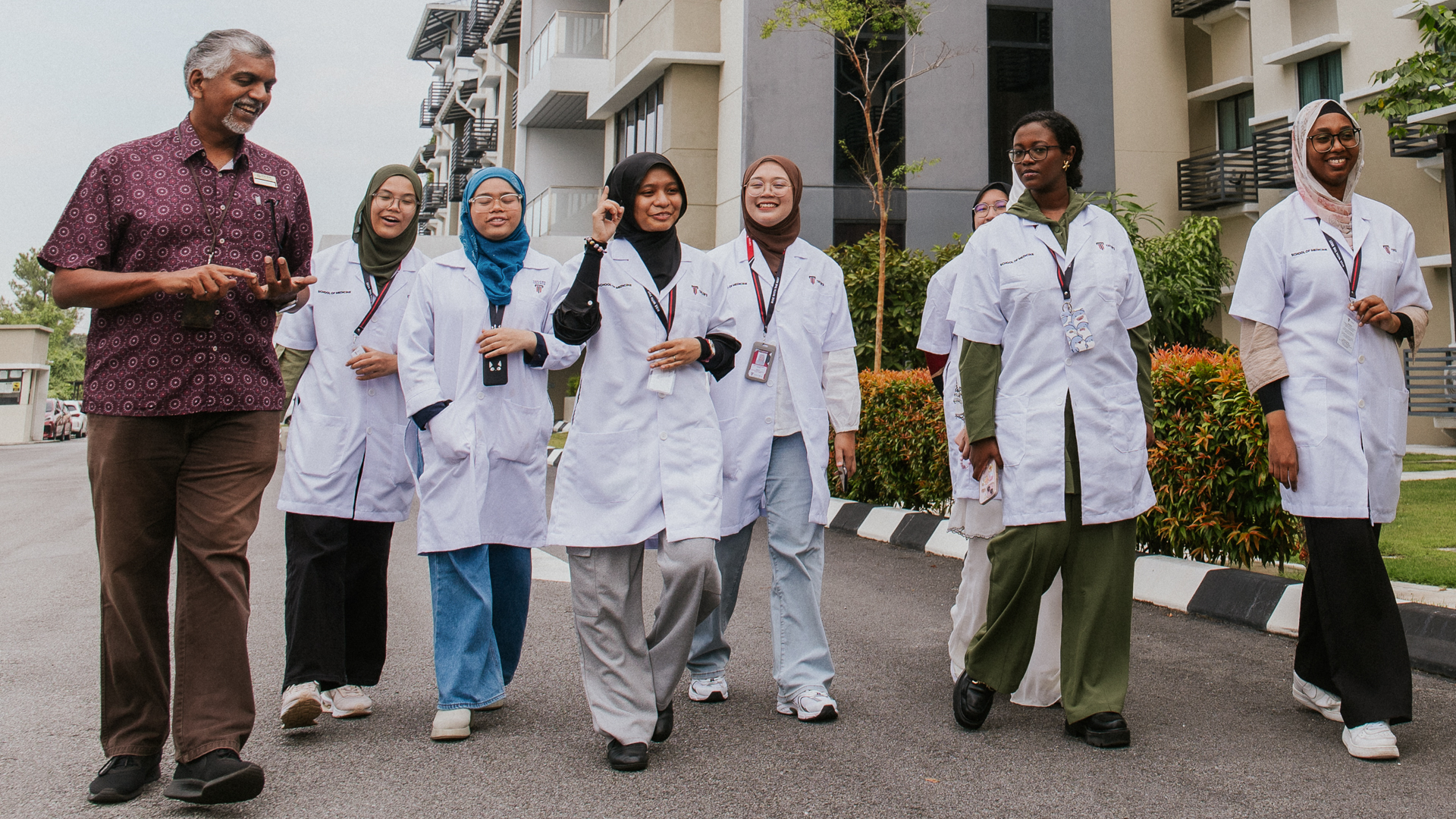 Taylor's medical students in white lab coats walking together with male lecturer