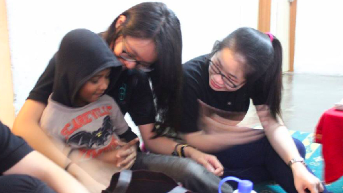 Two Taylor's Pharmacy students guiding a young child