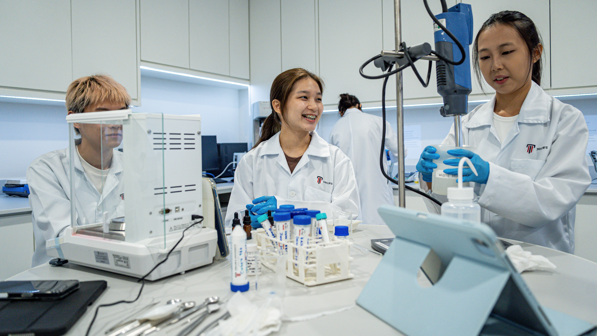 A scientist in a white lab coat and blue gloves in a pharmaceutical laboratory.