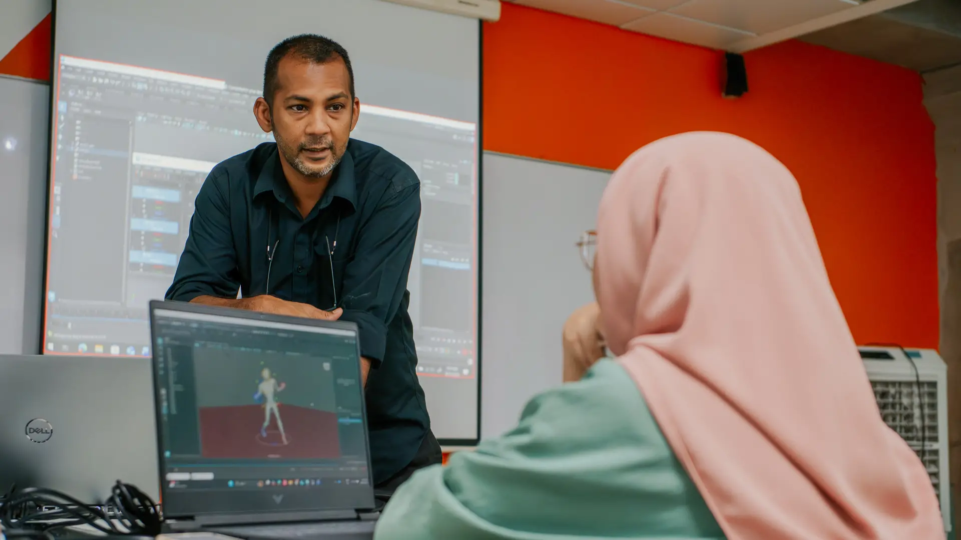 Lecturer guiding a student through digital animation and motion design software in a computer lab