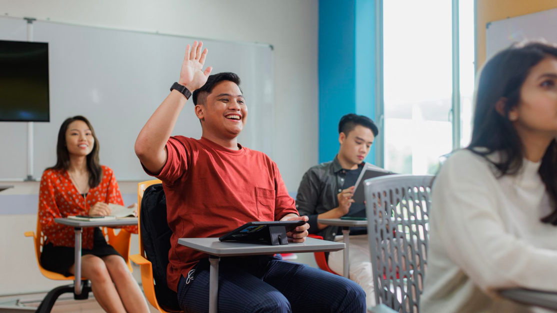 One student raising hand in the classroom to ask question